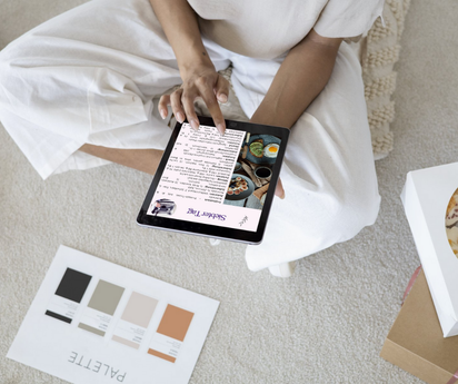 Sitzende Mama hält Tablet mit Celestro MamaFit+ – Ernährungsplan „Siebter Tag“; gemütliche Szene am Boden mit Farbpalette.